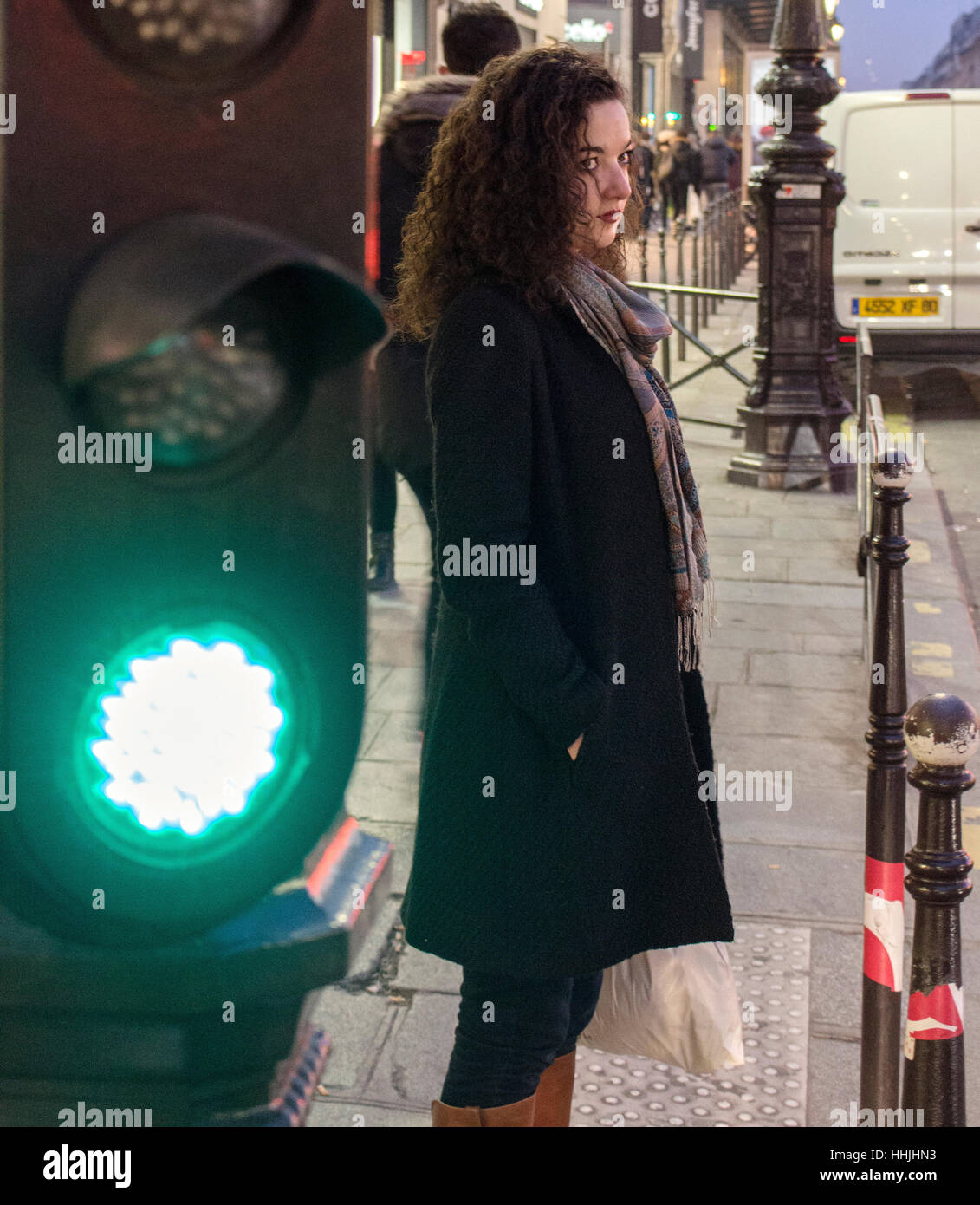 Frau wartet, die Straße überqueren. Die grüne Ampel steht neben ihr. Stockfoto