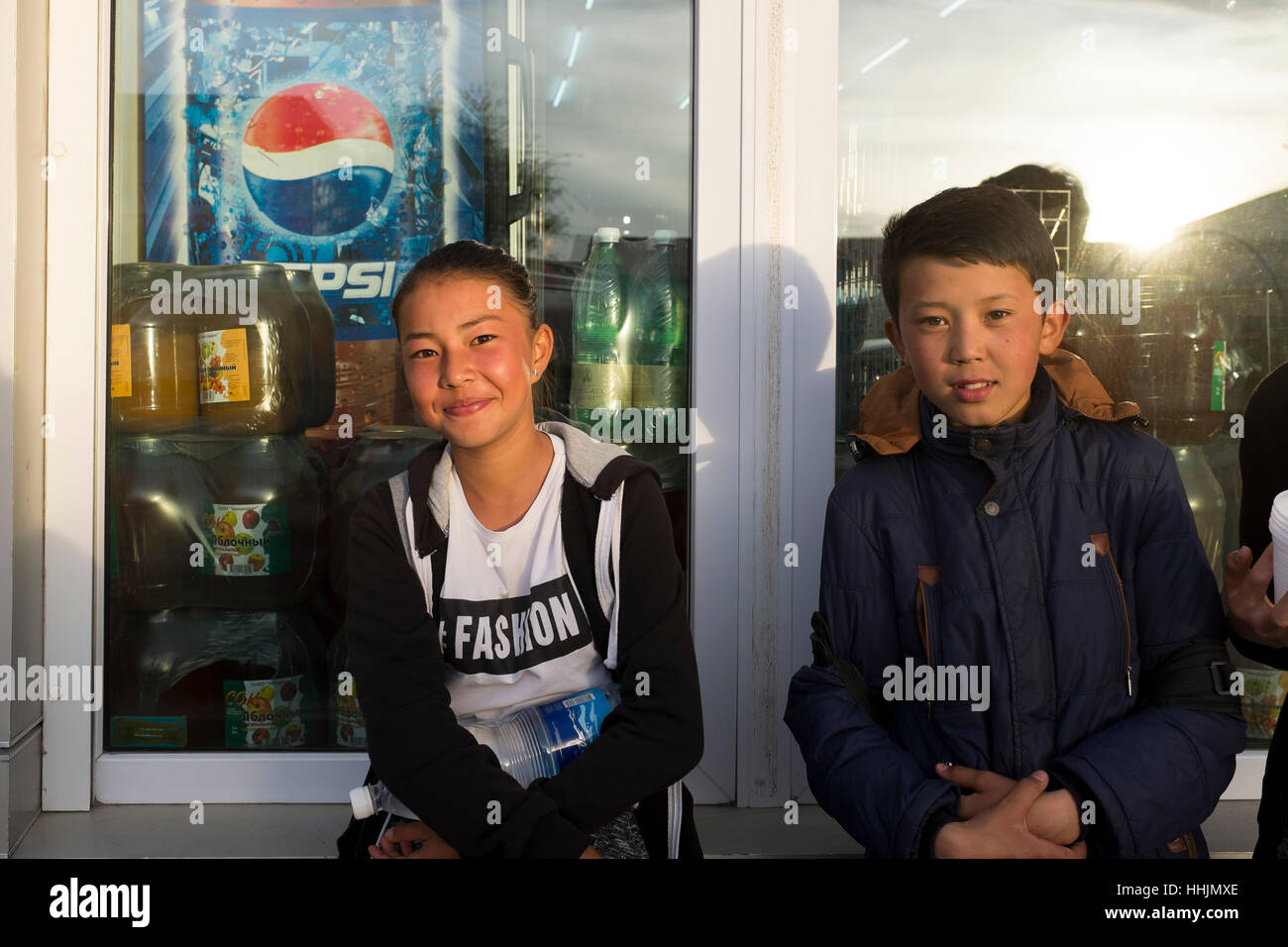 Ein Junge und ein Mädchen posieren vor einem kleinen Laden in der Kleinstadt Karakol im östlichen Teil Kirgisistans in Zentralasien. Stockfoto