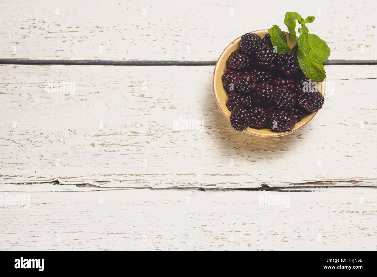 Brombeeren in einer Schüssel mit Minze auf weißem Hintergrund mit Platz für Kopie aus Holz Stockfoto