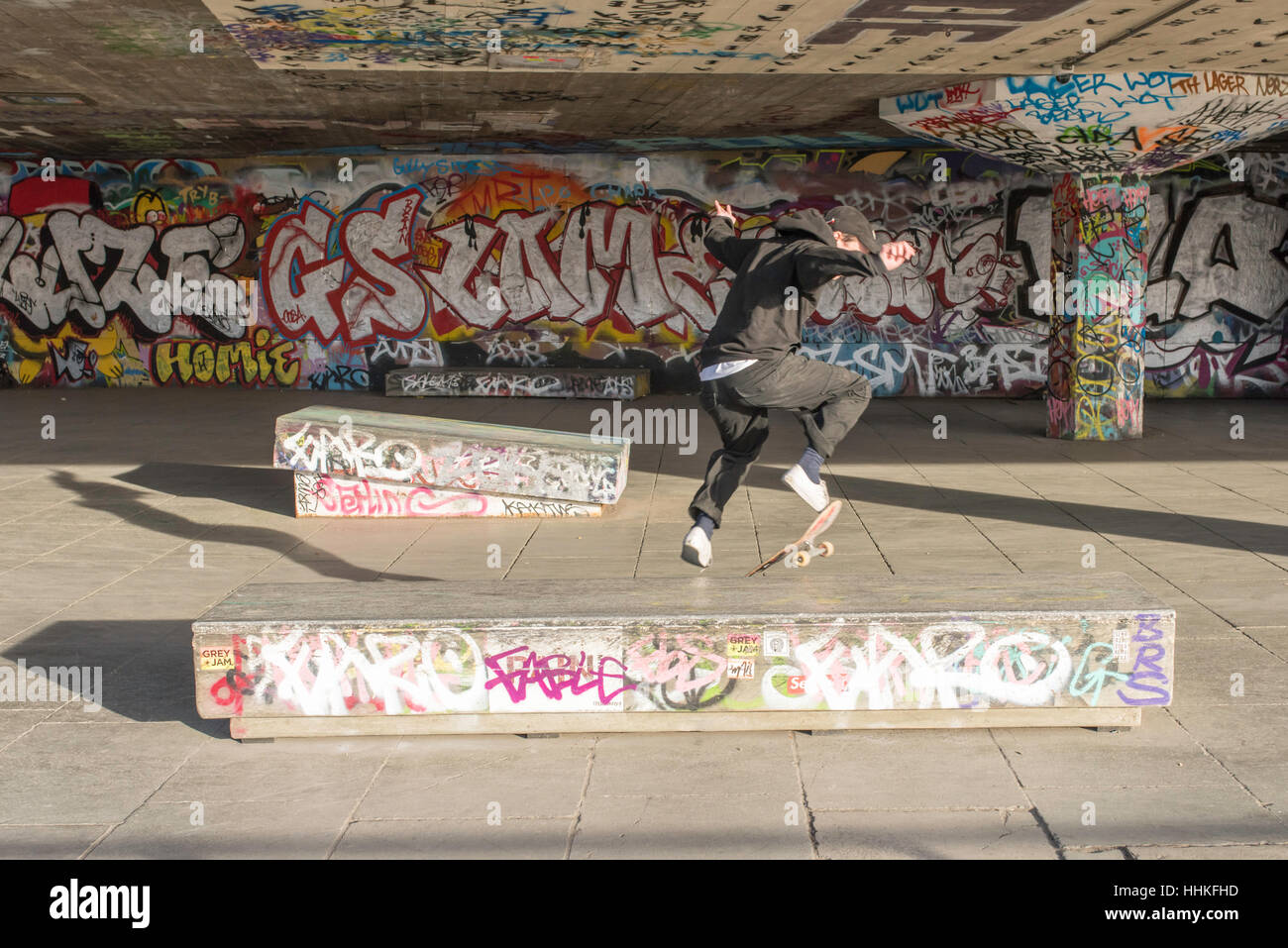 Ein Skate-Boarder Durchführung einen Sprung an einem sonnigen Nachmittag in der South Bank, London. Stockfoto