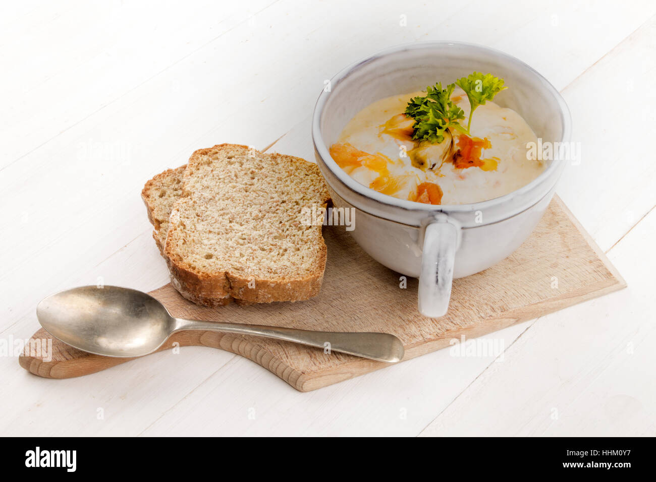 schottische Fischsuppe in eine Tasse und zwei Brotscheiben Soda auf einem Holzbrett Stockfoto