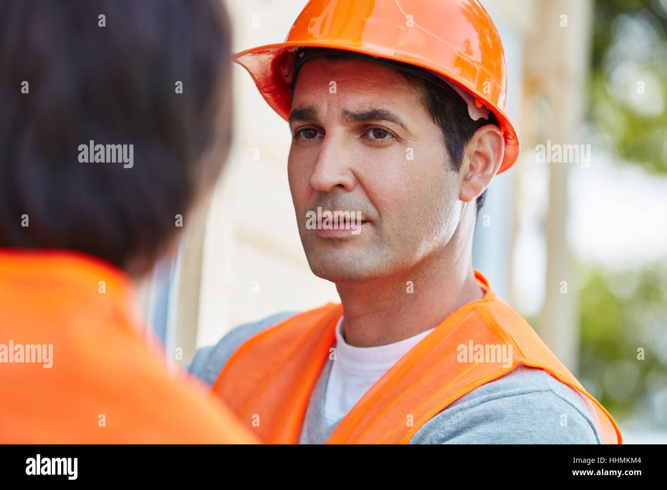 Der Mensch als Bauarbeiter mit orange Bauarbeiterhelm Stockfoto