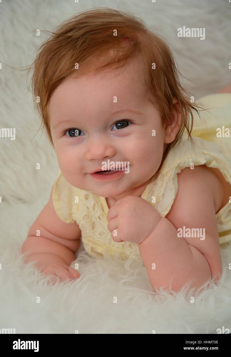 Porträt von lächelndes Babymädchen, sechs Monate liegen auf weißem Fell, Schweden Stockfoto