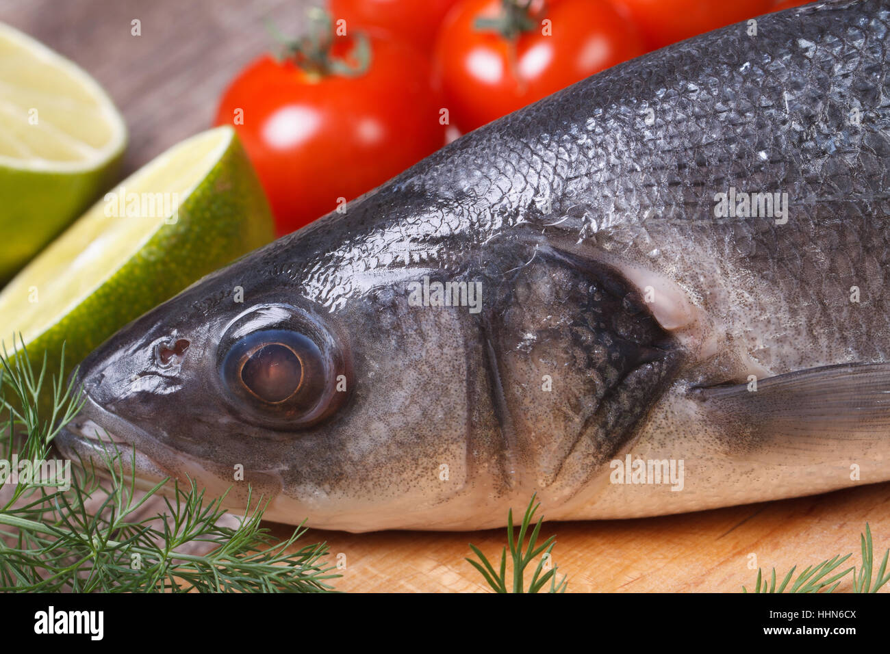 Roher Seebarsch Fisch auf Schneidebrett mit Gemüse Nahaufnahme Horizontal. Stockfoto