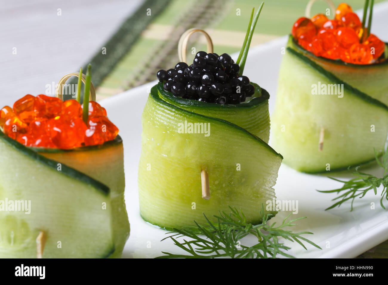 Gurke rollt auf einem weißen Teller Closeup gefüllt mit roten und schwarzen Kaviar Stockfoto