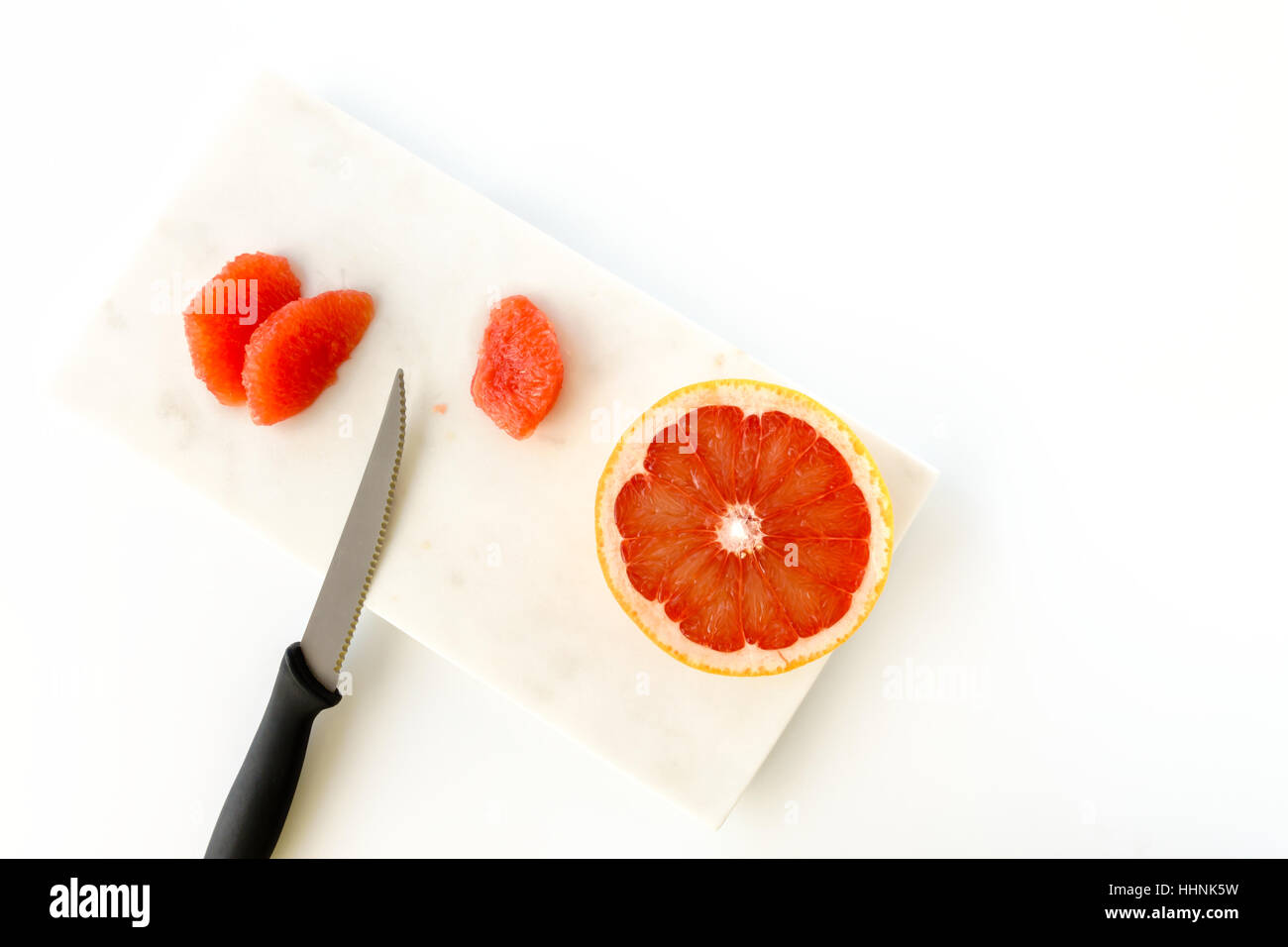 Roter Grapefruit und Messer auf Marmor Schneidebrett Stockfoto