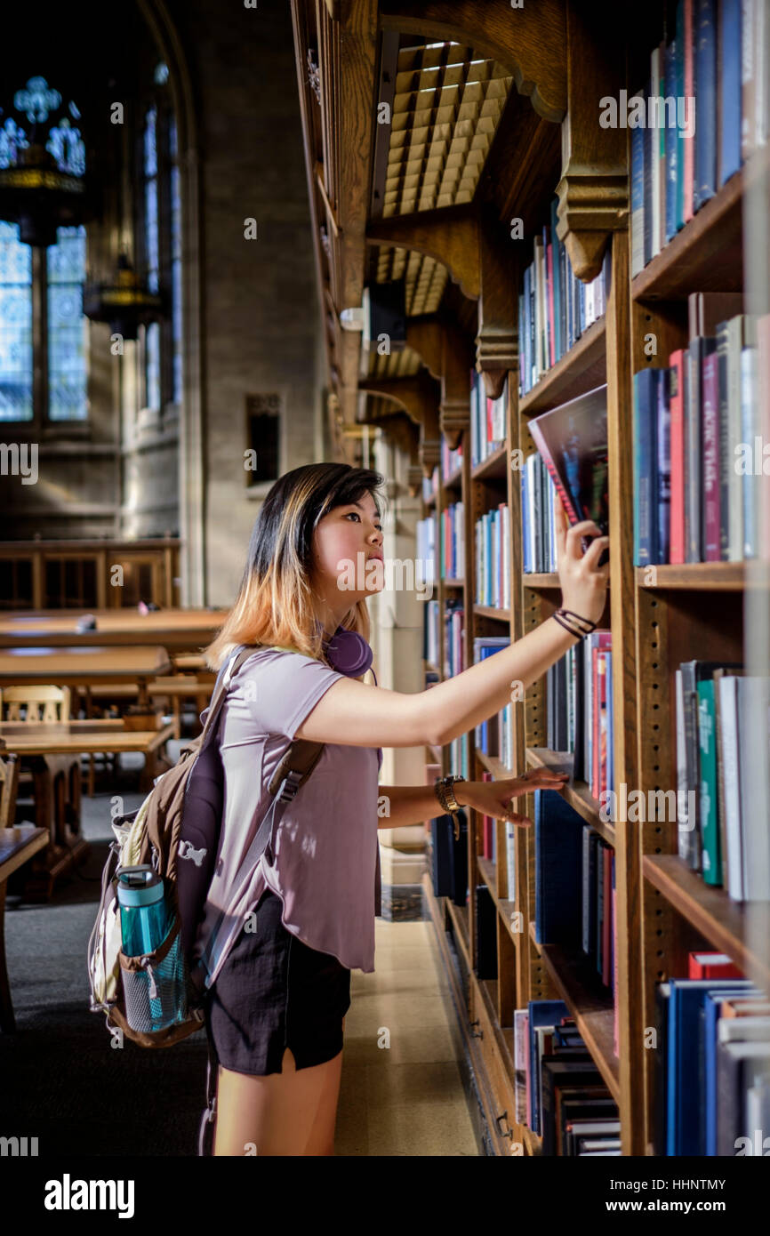 Chinesische Frau, die in Bibliothek Buch auswählen Stockfoto