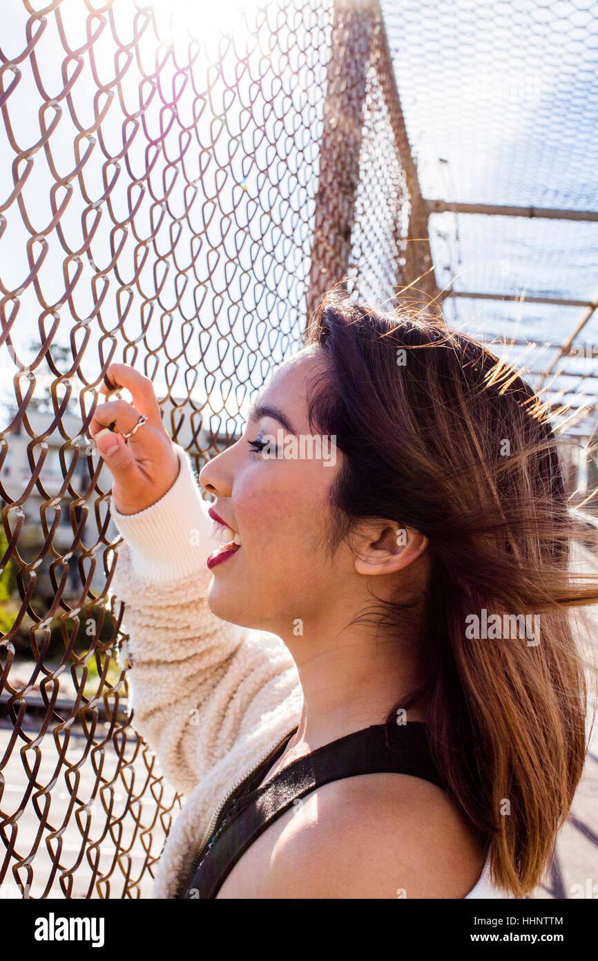 Lächelnde asiatische Frau Steg Maschendrahtzaun Festhalten Stockfoto
