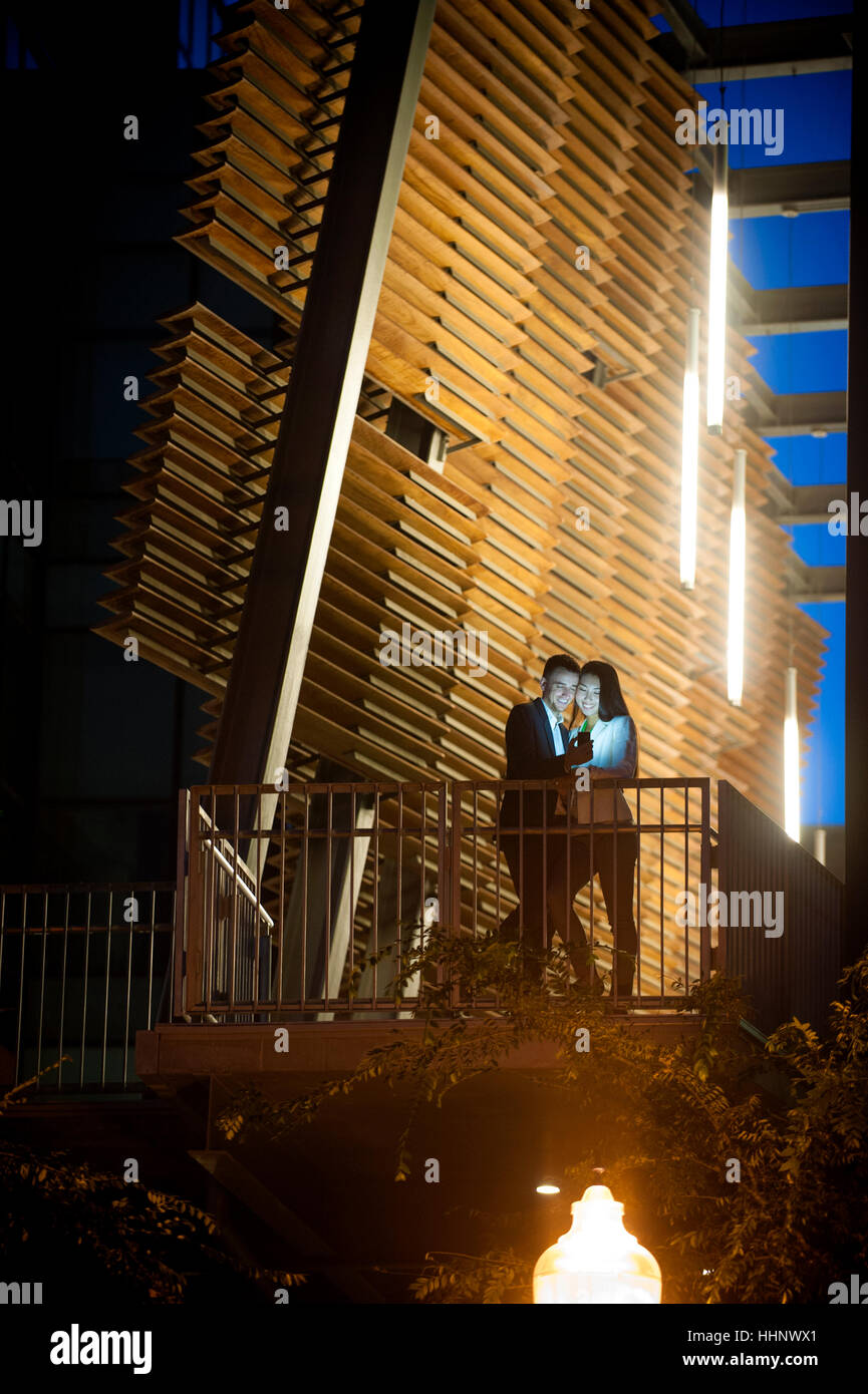 Paar steht auf Balkon posiert für Handy Selfie nachts Stockfoto