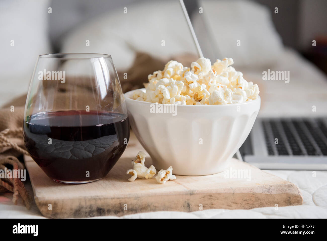Schüssel Popcorn und ein Glas Wein in der Nähe von laptop Stockfoto