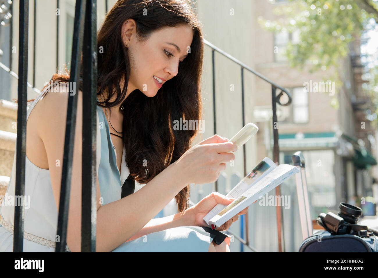 Thai Frau sitzen auf städtischen Treppe mit Handy und Ratgeber Stockfoto