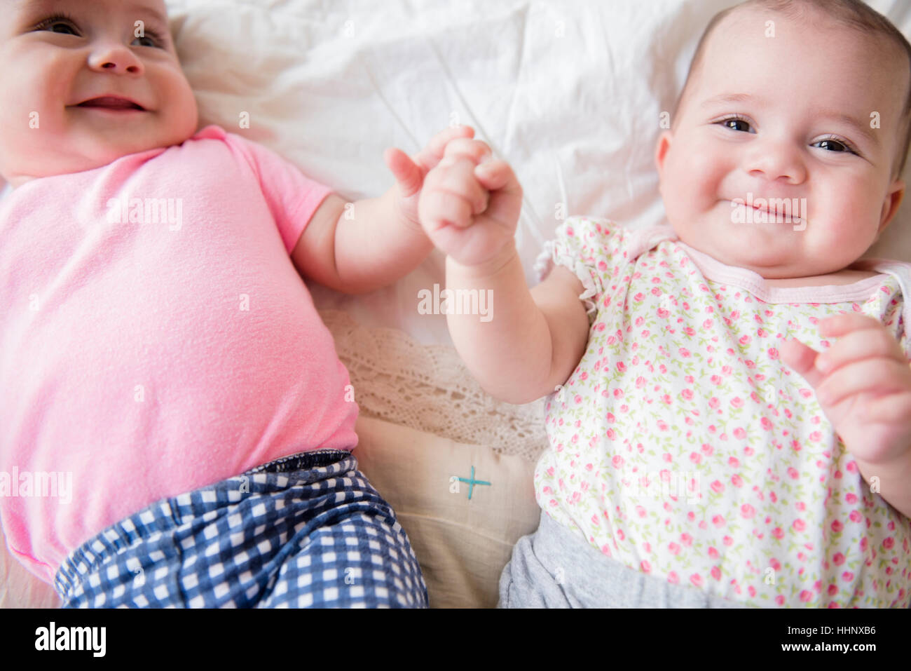 Kaukasische Twin Baby Mädchen lächelnd auf Bett Stockfoto