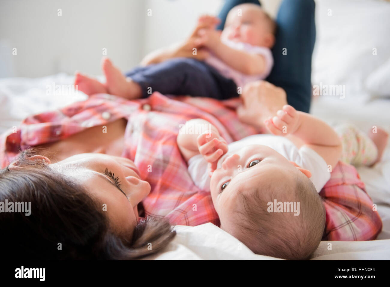 Kaukasische Mutter mit auf Bett mit Baby Zwillingstöchter Stockfoto
