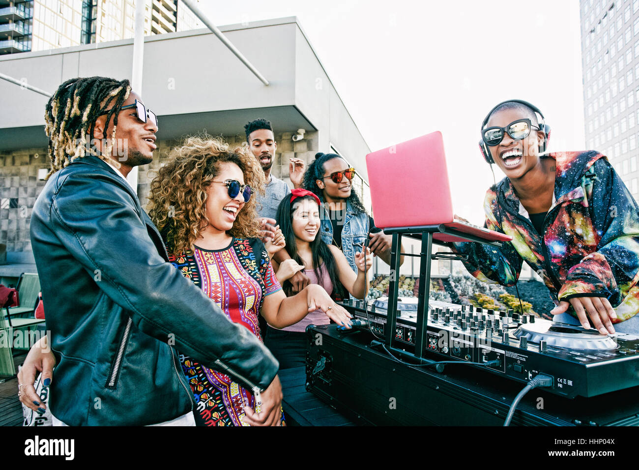 Freunde lächelnd mit DJ auf städtischen Dach Stockfoto