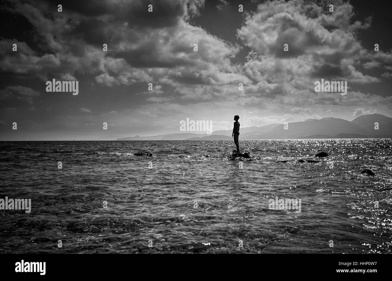 Silhouette des kaukasischen Junge stand auf Felsen im Meer Stockfoto