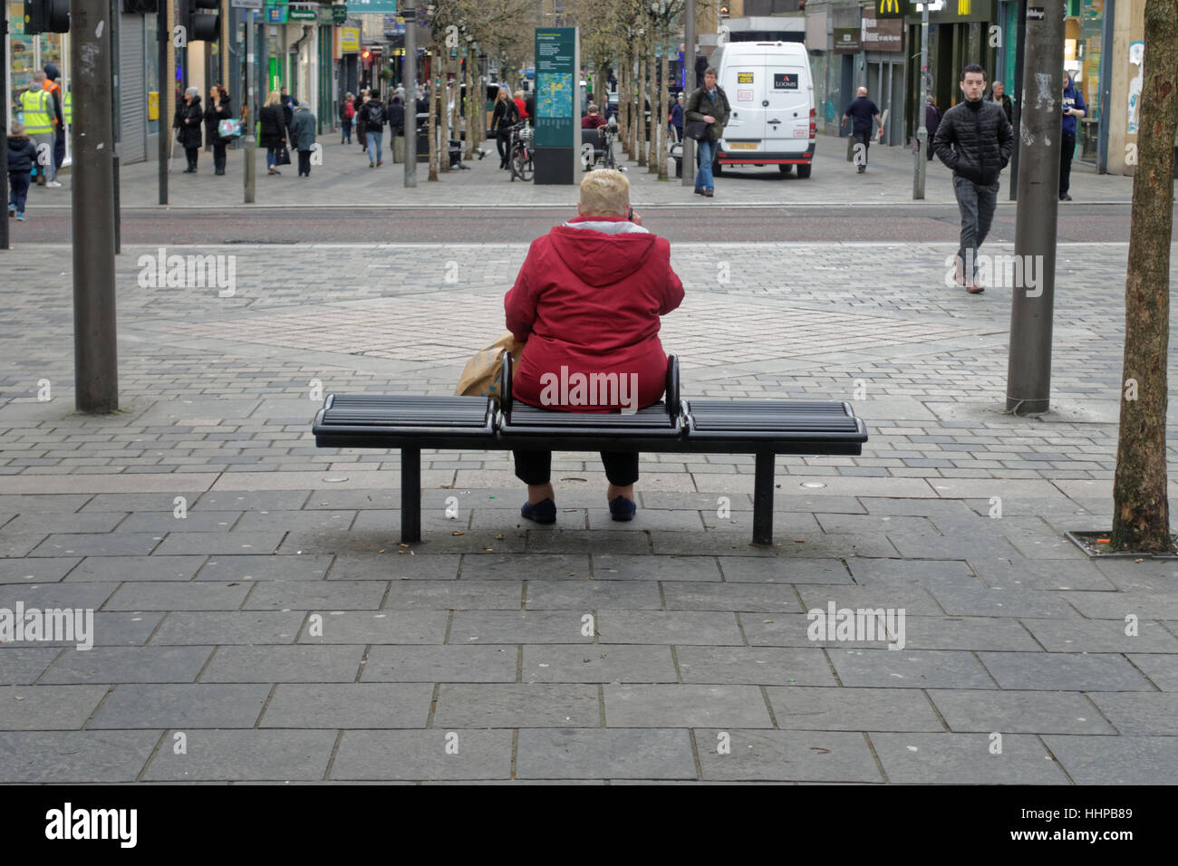 große alte Dame auf dem Handy in rot sitzen auf Straße Bank Sauchiehall Street Glasgow, Stockfoto