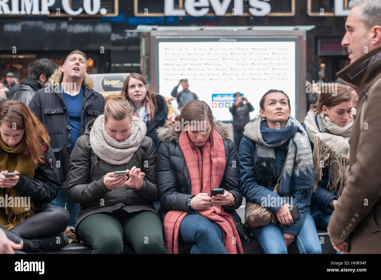 New York, USA. 20. Januar 2017. Millennials SMS auf dem Times Square in New York während der Anzeige von der Einweihung des Donald Trump als 45. Präsident der Vereinigten Staaten auf Großleinwand ABC Fernsehen am Freitag, 20. Januar 2017. Bildnachweis: Richard Levine/Alamy Live-Nachrichten Stockfoto