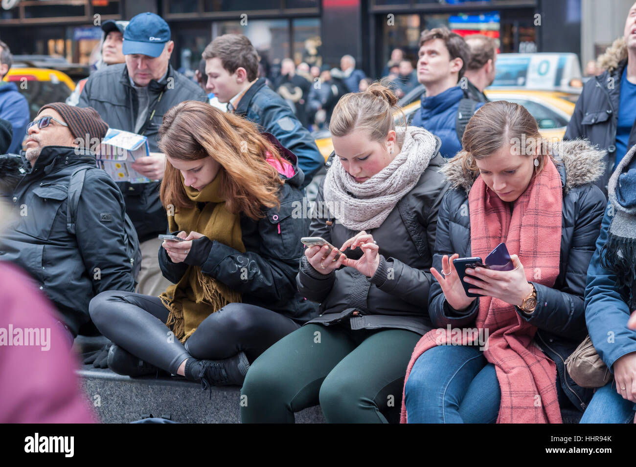 New York, USA. 20. Januar 2017. Millennials SMS auf dem Times Square in New York während der Anzeige von der Einweihung des Donald Trump als 45. Präsident der Vereinigten Staaten auf Großleinwand ABC Fernsehen am Freitag, 20. Januar 2017. Bildnachweis: Richard Levine/Alamy Live-Nachrichten Stockfoto