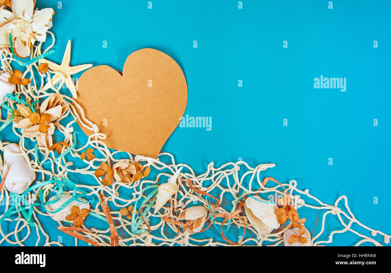 braune Papierherz in nautischen Saldierung mit Muscheln und Seesternen auf Türkis lackiertem Holz Stockfoto