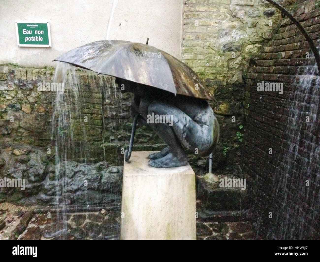 Brunnenskulptur Person unter Dach mit Wasser fallen von oben Stockfoto