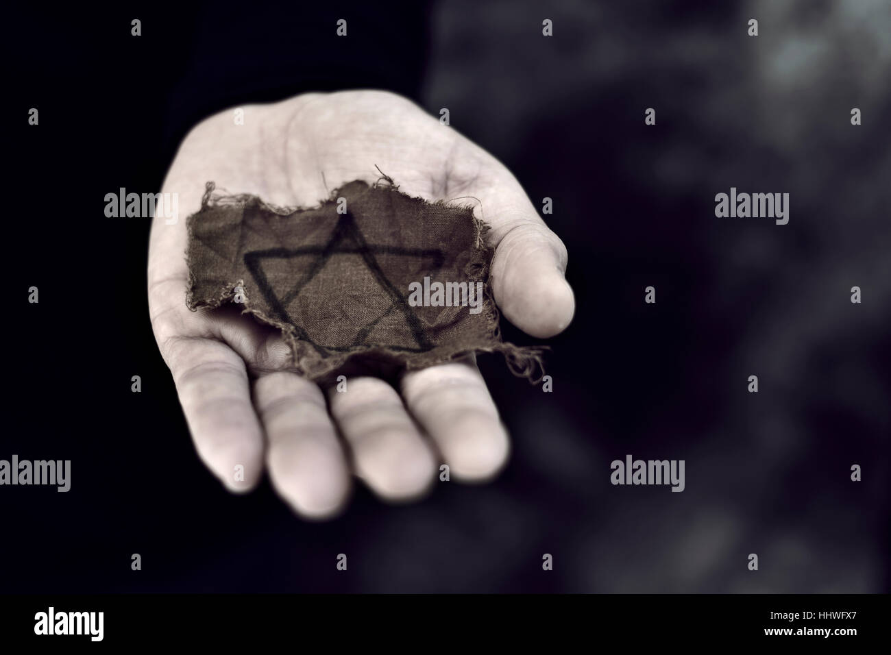 Nahaufnahme eines zerlumpten jüdisches Abzeichen in der Handfläche eines jungen Mannes Stockfoto