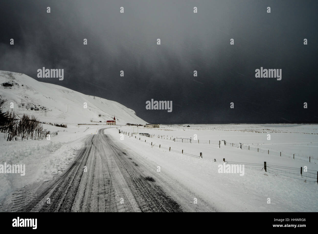 Weg durch Schnee bedeckt Landschaft unter Gewitterhimmel, Vik, Island Stockfoto