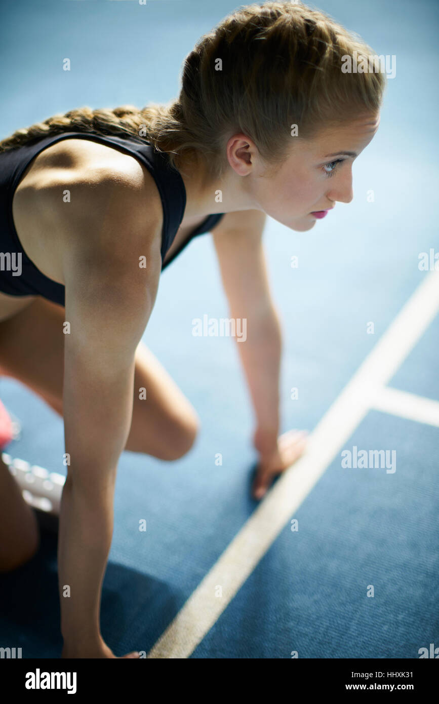 Verfolgen Sie ernsthafte fokussierte weibliche Läufer im Startblock auf Sport bereit Stockfoto