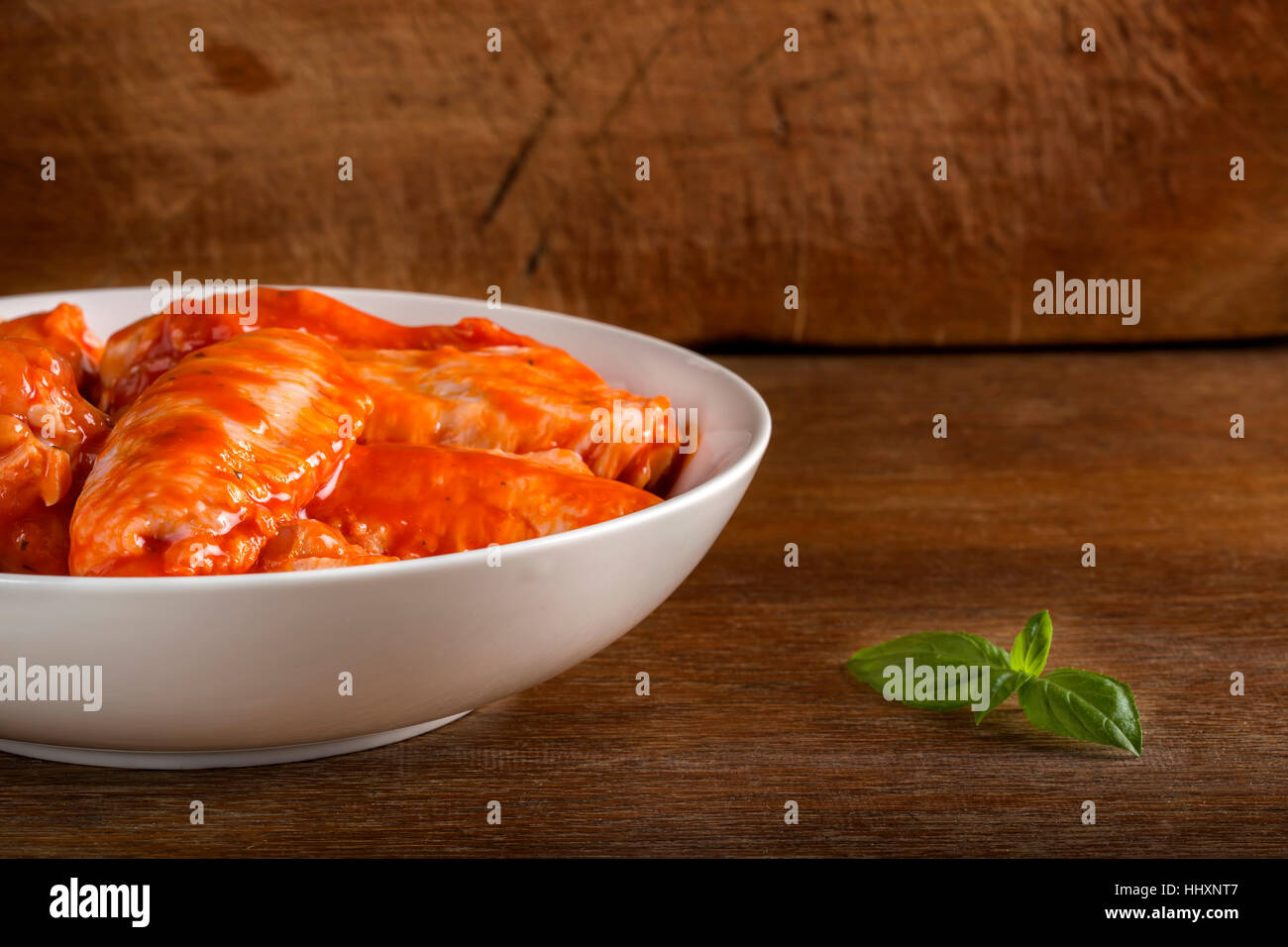 Schüssel mit Marinierte Hühnerflügel über hölzerne Hintergrund und kopieren Sie Raum Stockfoto