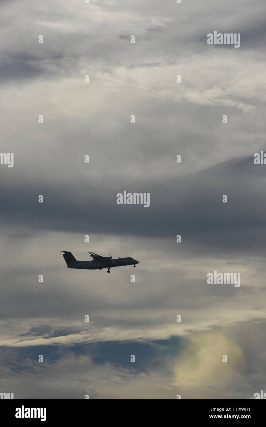 Ein kleines Verkehrsflugzeug ist bei einer Flughafenlandung gegen einen bewölkten Himmel silhouettiert Stockfoto