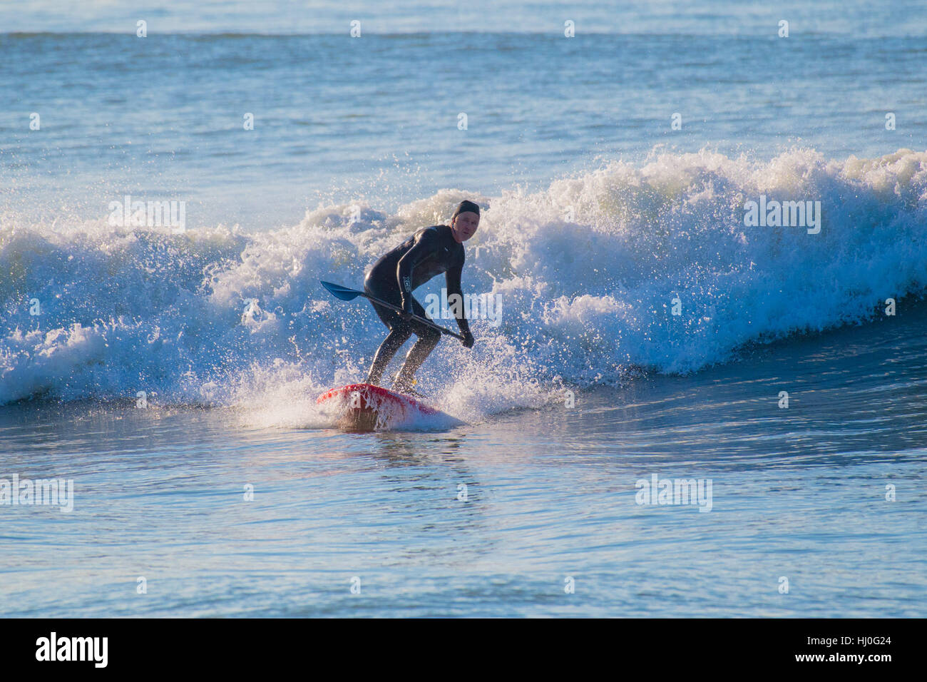 Aberystwyth Wales UK, Samstag, 21. Januar 2017 UK Wetter: nach einer eisigen, kalten Nacht mit Temperaturen weit unter Null, ein Mann genießt einen schönen Tag Sonnenstrahlen Surfen die Wellen am Strand in Aberystwyth auf die Cardigan Bay Küste Westwales Foto Keith Morris / Alamy Live News Stockfoto