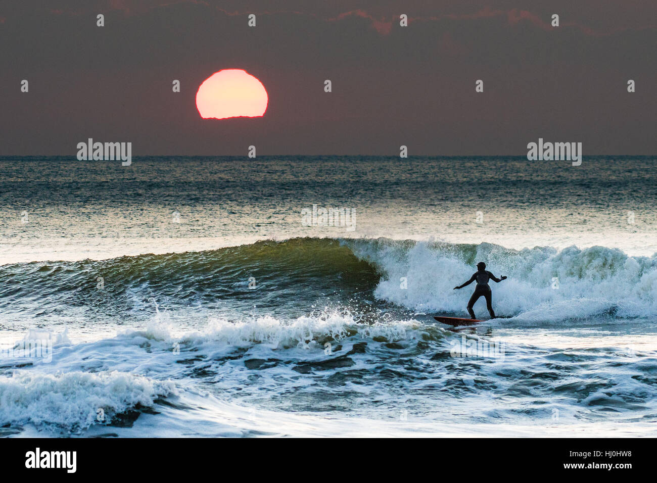 Aberystwyth Wales UK, Samstag, 21. Januar 2017 UK Wetter: nach einer eisigen, kalten Nacht mit Temperaturen weit unter Null, Surfer genießen Sie die Wellen bei Sonnenuntergang am Ende ein schöner Tag Sonnenstrahlen in Aberystwyth auf die Cardigan Bay Küste Westwales Foto Keith Morris / Alamy Live News Stockfoto