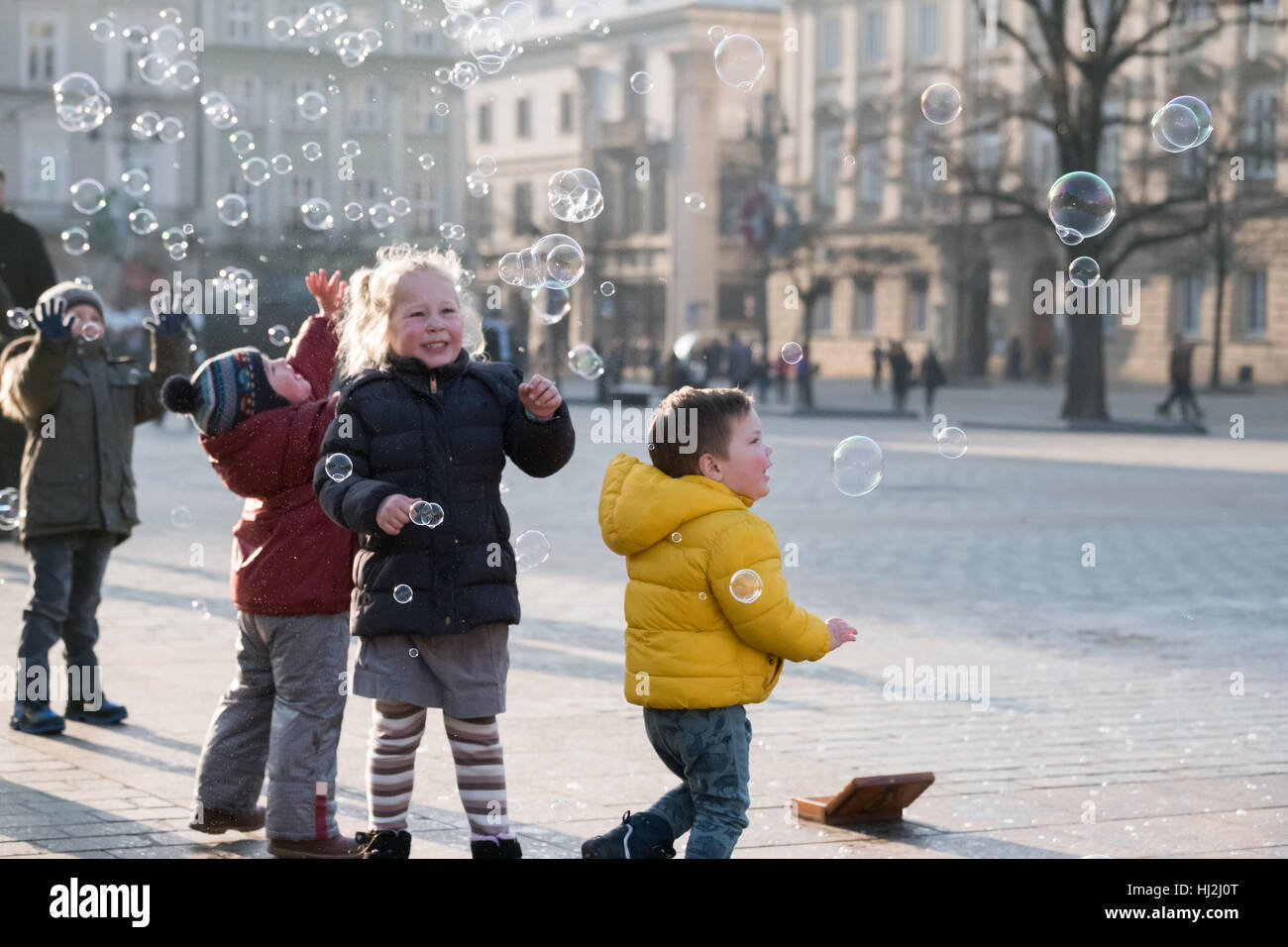 Kinder Alter von 4-5 Jahren mit Seifenblasen auf dem Platz spielen Stockfoto