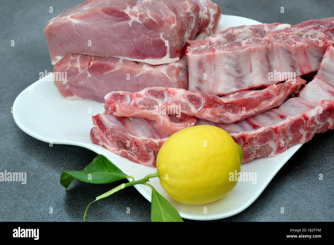 Tablett mit Schweinelende, Rippen und einer Zitrone Stockfoto