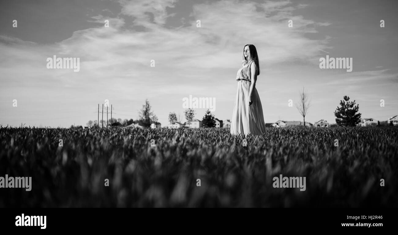 Frau in einem schönen langen Türkis Kleid posiert auf einer Wiese auf dem Rasen. Stockfoto