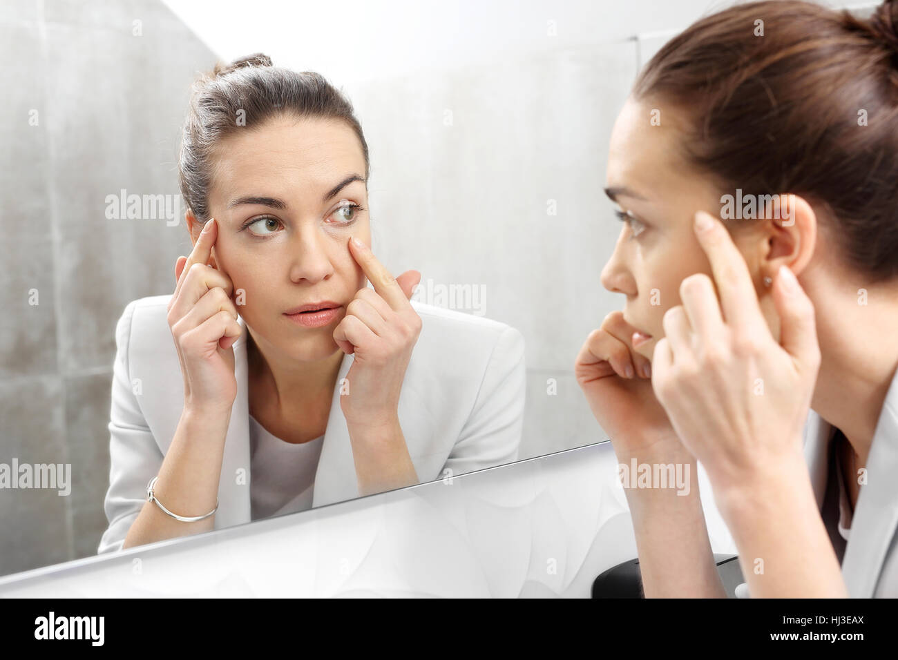Reflexion im Spiegel. Frau schaut in den Spiegel, bemerken die ersten Fältchen Stockfoto