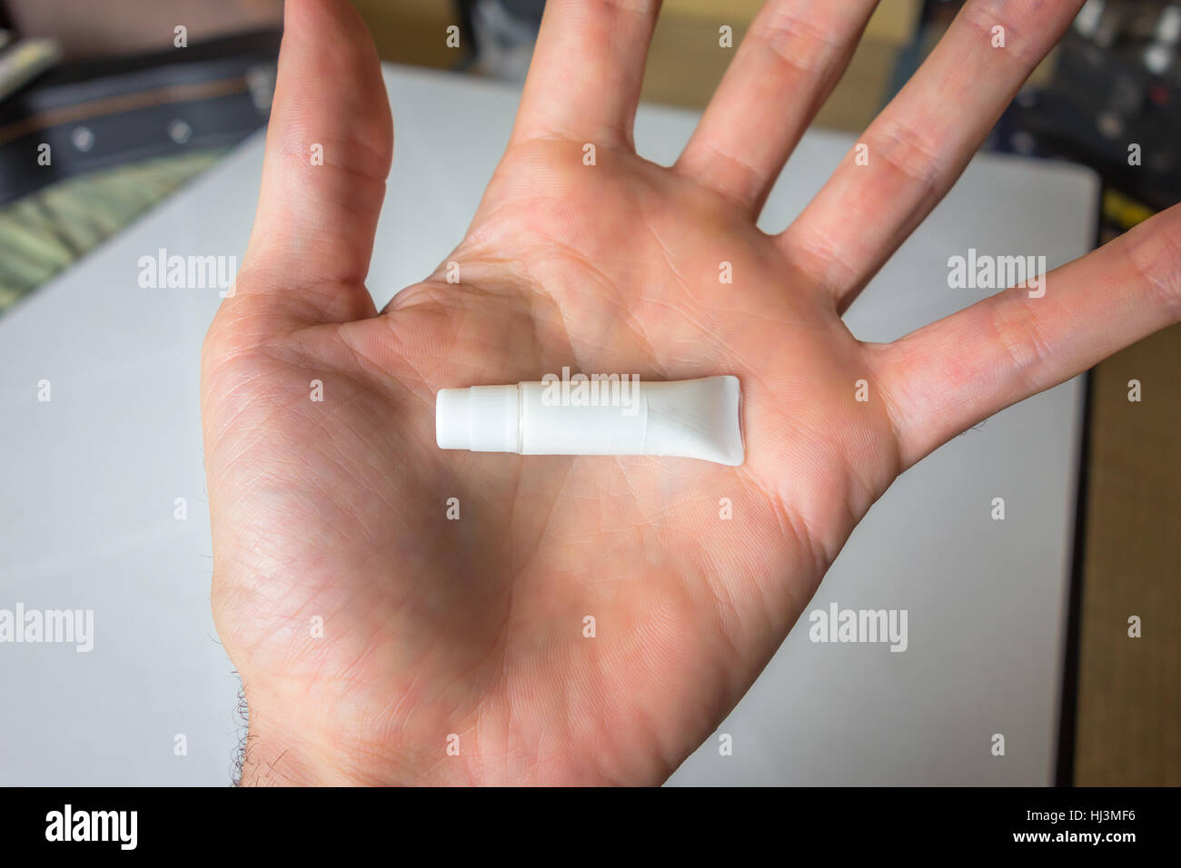 Eine winzige, unbeschriftete Röhrchen in der Handfläche einer Hand statt. Stockfoto