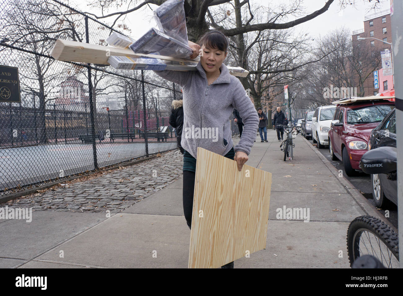 Eine chinesische Amerikanerin tragen und Bauholz zu einer Baustelle in Chinatown, Downtown Flushing, Queens, New York. Stockfoto