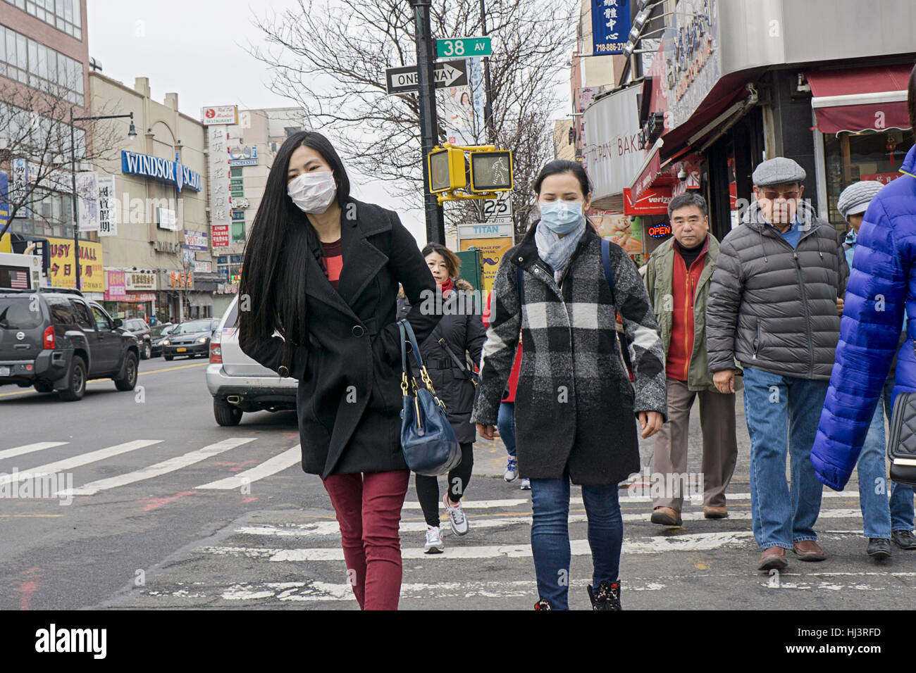 Zwei junge Chinesinnen chirurgische Masken überqueren einer stark befahrenen Straße auf der Main Street in CHinatown, Downtown Flushing, Queens, New York Stockfoto