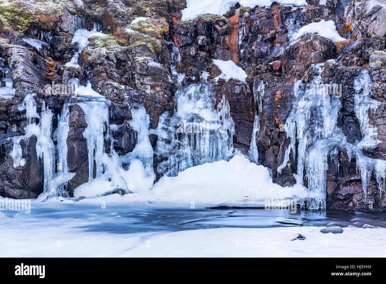 Ein gefrorenen Fluss im Hochland von Island eingerahmt von Pastell Himmel und zerklüftete Gelände bietet landschaftlich Inbegriff der gefrorenen Wildnis. Stockfoto