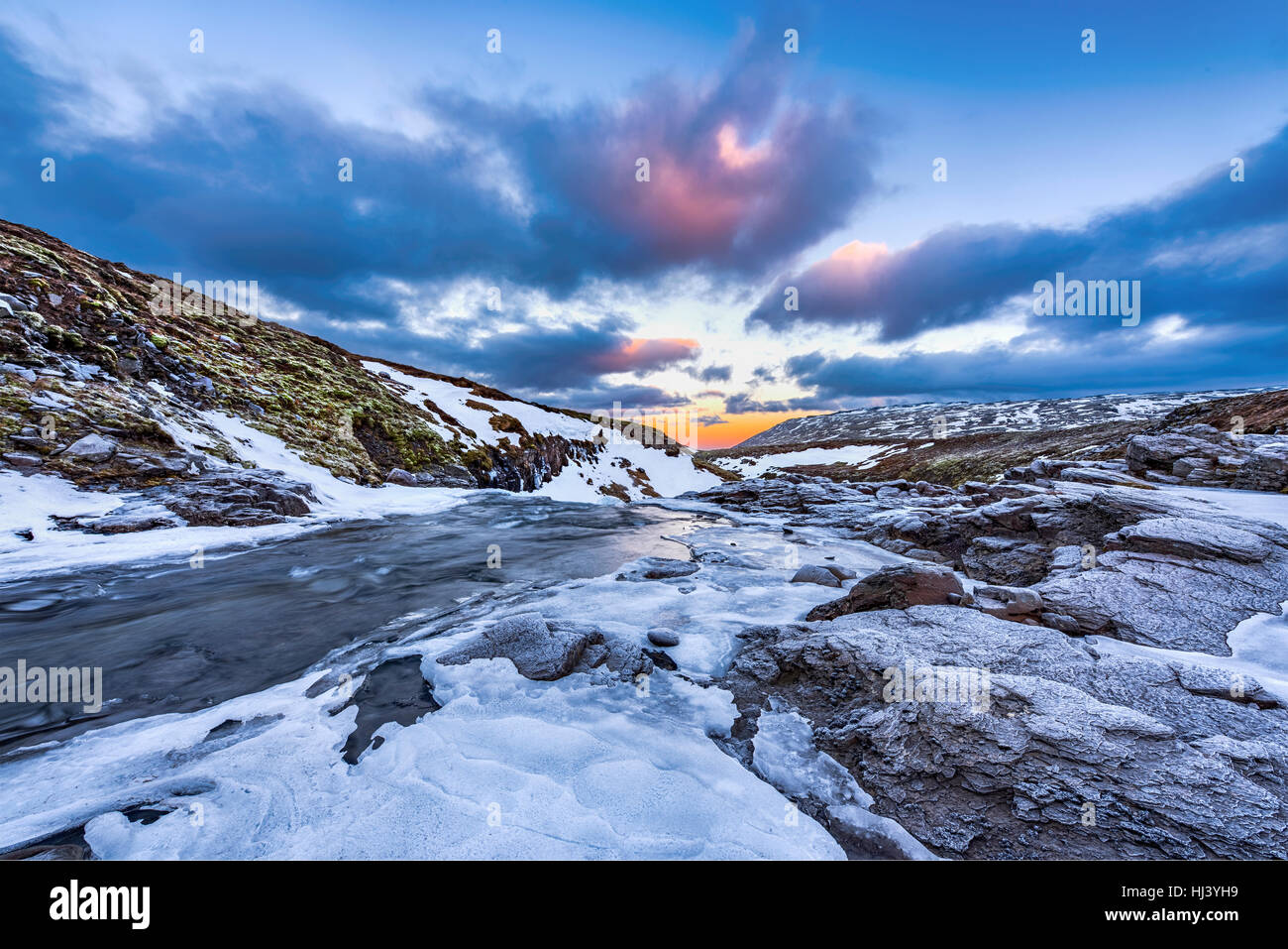 Ein kalten verschneiter Fluss im Hochland von Island eingerahmt von Pastell Himmel und zerklüftete Gelände bietet landschaftlich Inbegriff der gefrorenen Wildnis. Stockfoto