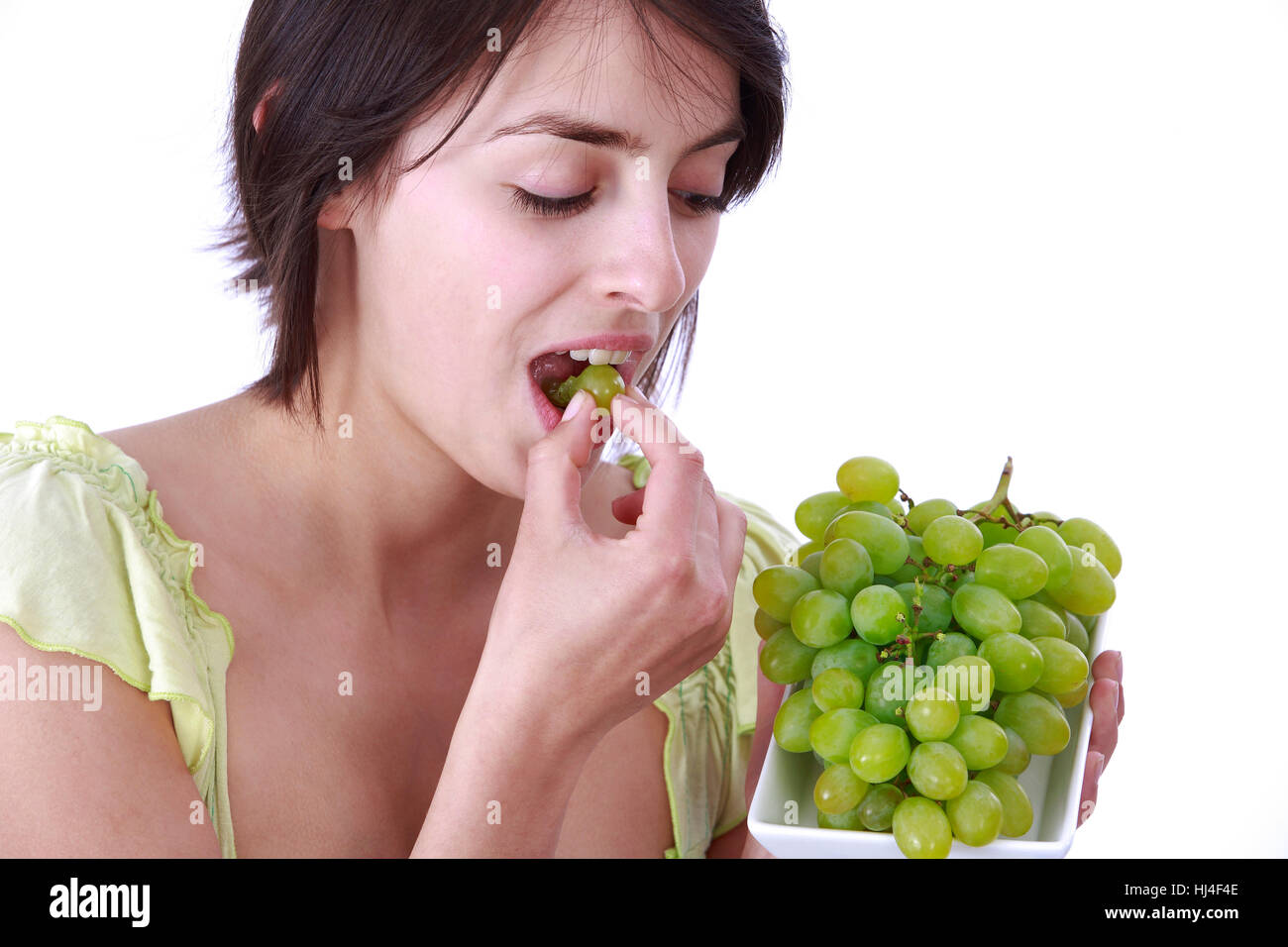 Junge Frau isst Trauben Stockfoto