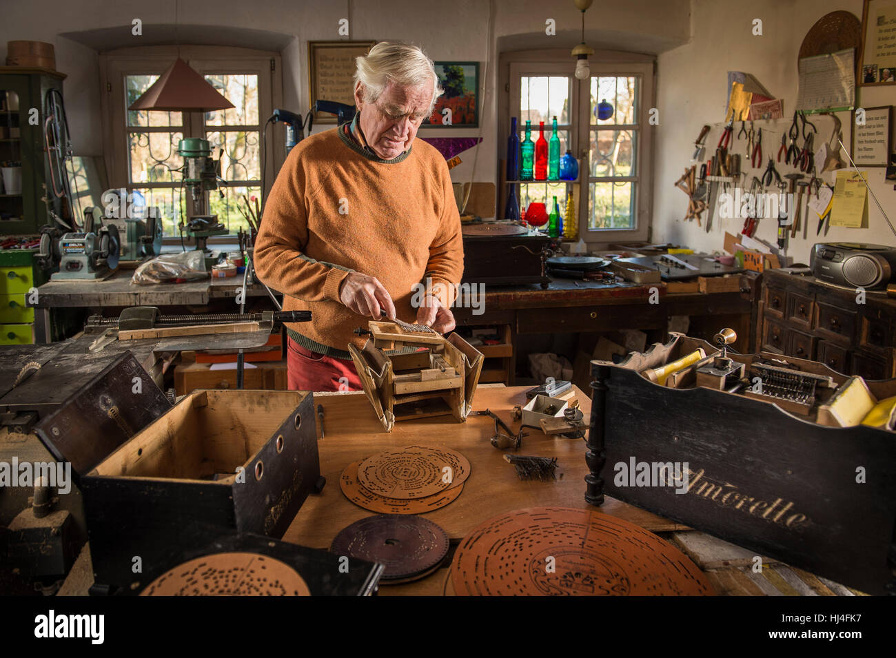 Drehorgel-Generator, Werkstatt, Man prüft Frühling Drähte der Stimmstock auf Körper, leerer Koffer auf den linken, perforierten Platten vor Stockfoto
