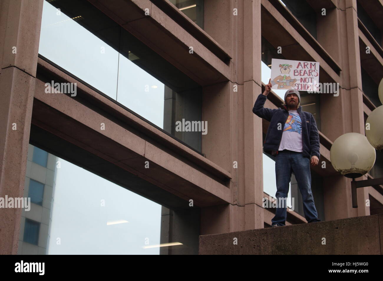 Distrikt von Columbia, USA. 21 Jan, 2017. Ein Mann steht auf einer Brücke, mit einem Schild mit der Aufschrift "ARM TRÄGT NICHT der Schulen neben einer Abbildung von Yogi Bear Besitz einer Waffe. Stockfoto