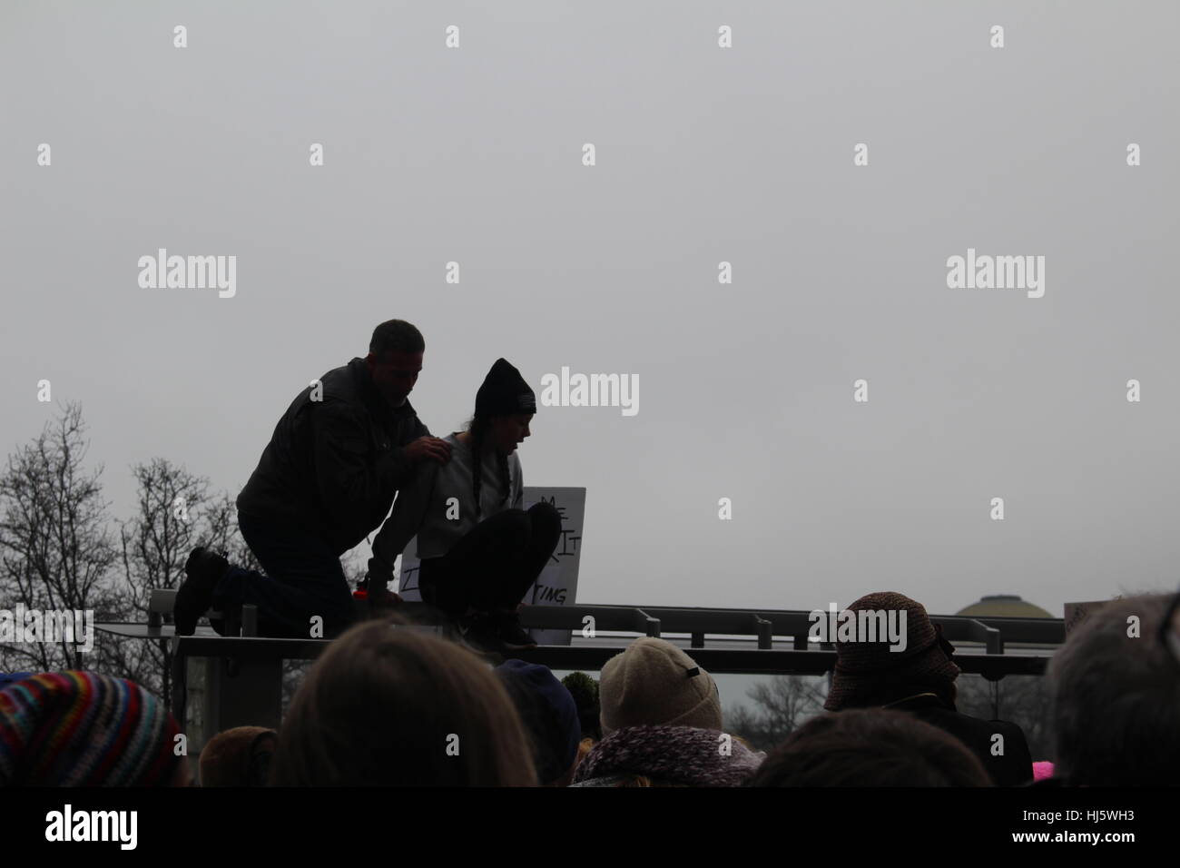 Distrikt von Columbia, USA. 21 Jan, 2017. Ein Mann hilft einer Frau, klettern Sie auf die Oberseite einer Bushaltestelle einen besseren Blick auf den Livestream zu erhalten. Stockfoto