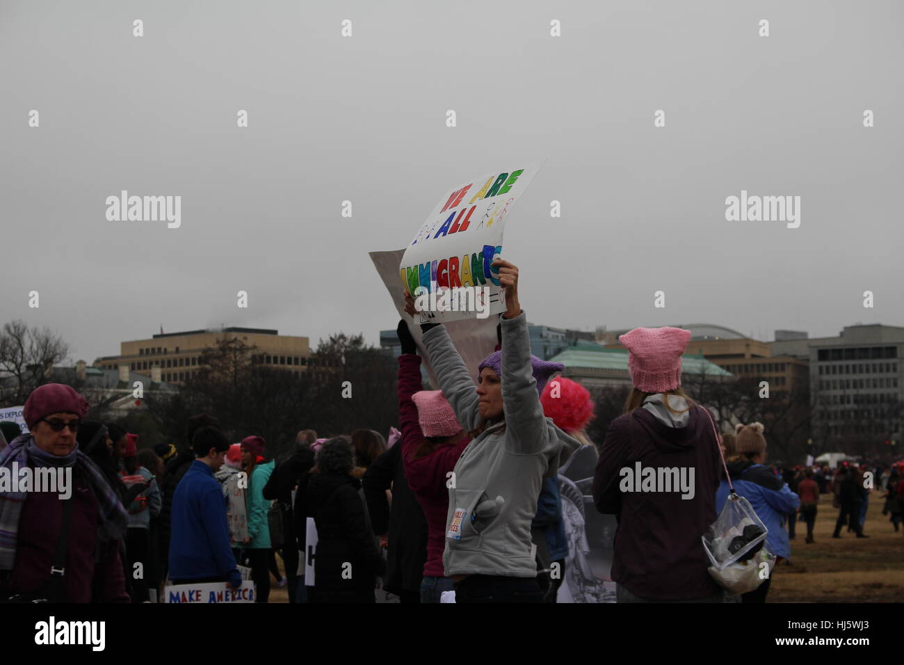 Distrikt von Columbia, USA. 21 Jan, 2017. Eine Frau auf dem Rasen des Weißen Hauses hält ein Schild mit der Aufschrift "WIR SIND ALLE MIGRANTINNEN". Stockfoto