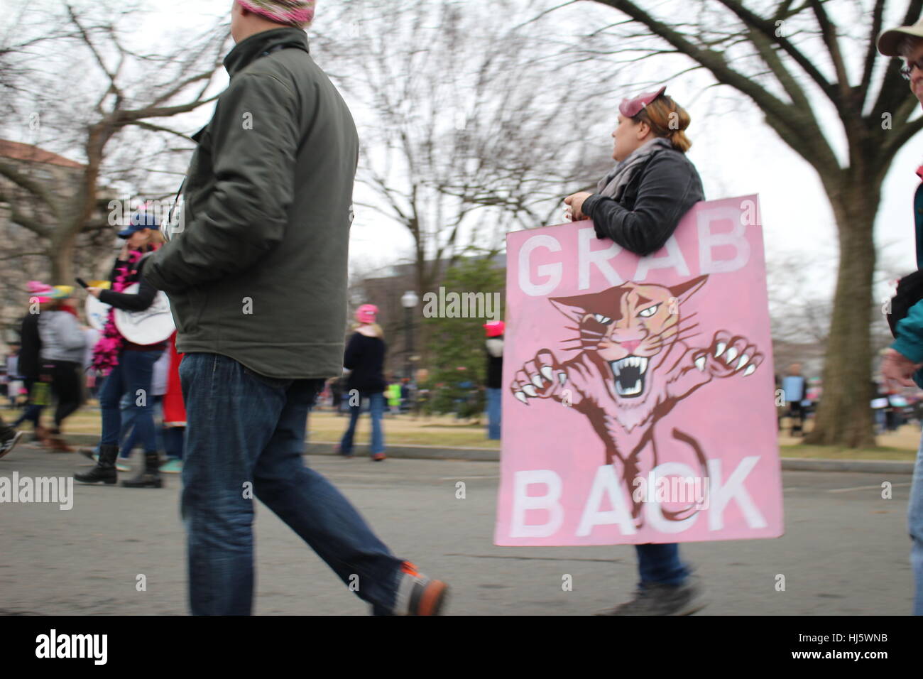 Distrikt von Columbia, USA. 21 Jan, 2017. Eine Frau geht entlang einer Straße neben dem Rasen des Weißen Hauses mit einem Schild mit der Darstellung eines stürzen sich Jaguar mit der Bildunterschrift "GRAB/ZURÜCK'. Stockfoto