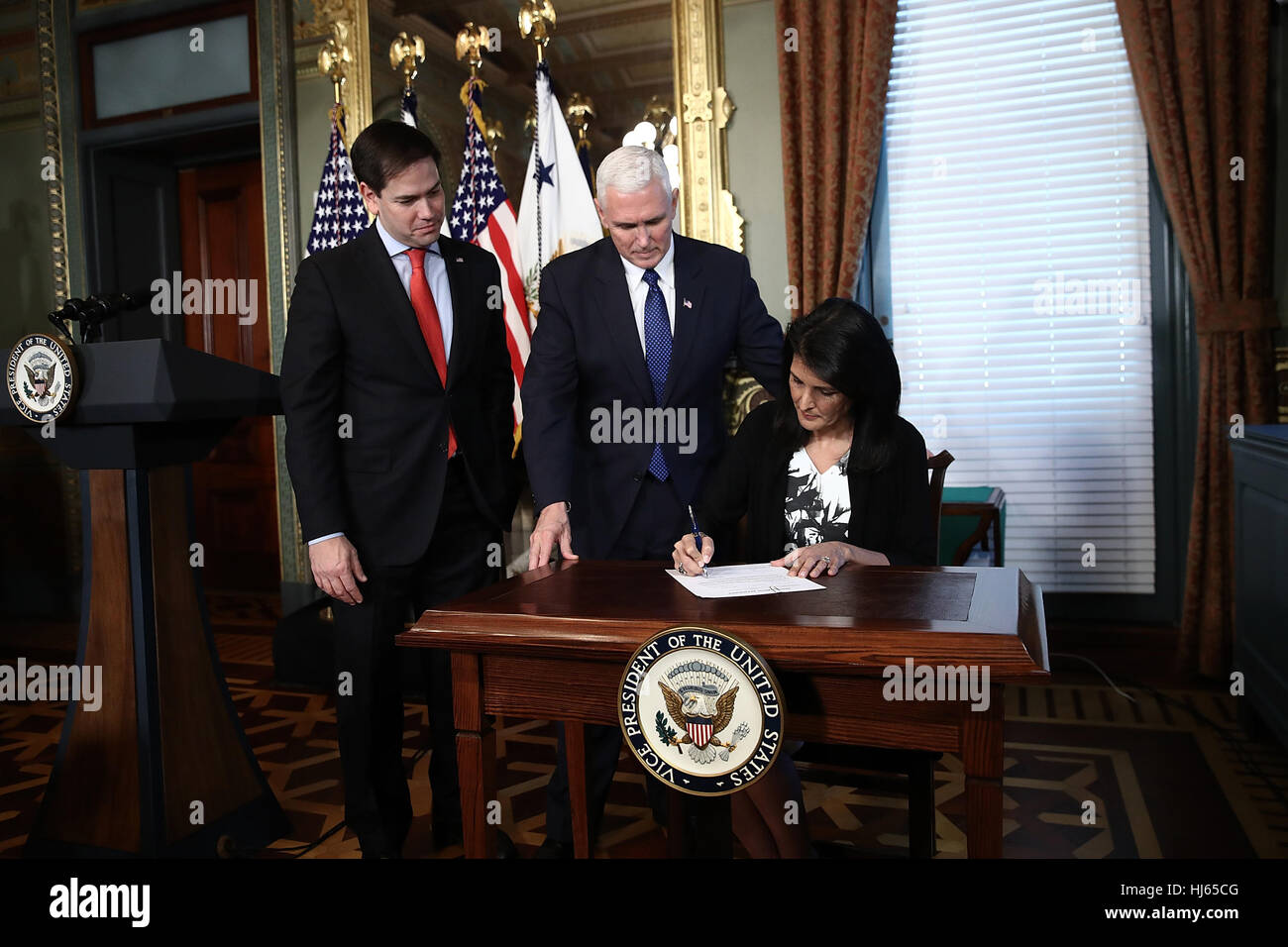 Washington, DC, USA. 25. Januar 2017. Nikki Haley schildern ihre Bestätigung der Ernennung Papierkram wie U.S. Vice Presdient Mike Pence (C) am Ende der Ceremomy wo wurde Haley als US-Botschafter bei den Vereinten Nationen 25. Januar 2017 in Washington, DC, USA vereidigt aussieht. Haley war früher der Gouverneur von South Carolina. Auch abgebildet ist Vereinigte Staaten Senator Marco Rubio (Republikanische von Florida). Bildnachweis: Win McNamee/Pool über CNP - kein Draht-SERVICE - Foto: Win Mcnamee/konsolidiert News Fotos/Win McNamee - Pool über CNP Stockfoto