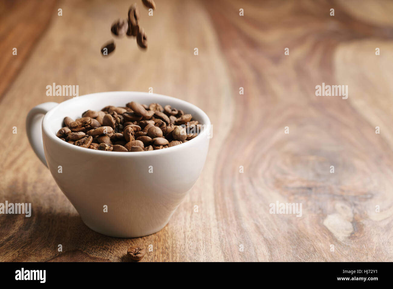 Cappuccino-Tasse mit gerösteten Kaffeebohnen auf Holztisch Stockfoto