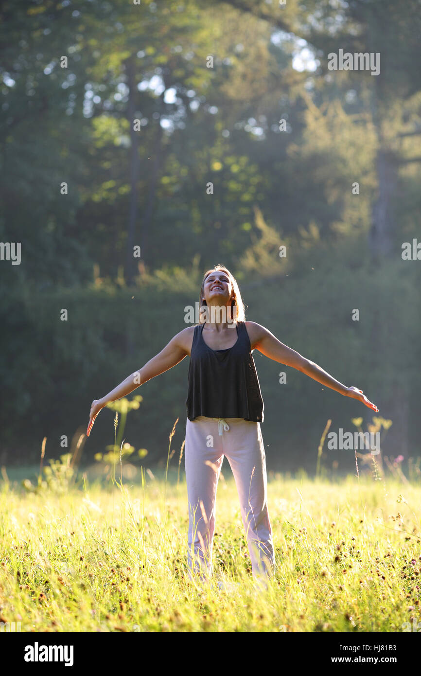 Glückliche junge Frau im Park mit Händen auf die Seite Stockfoto