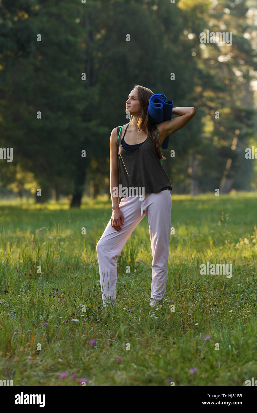 Schöne Mädchen wegsehen und hält Yoga-Matte im park Stockfoto